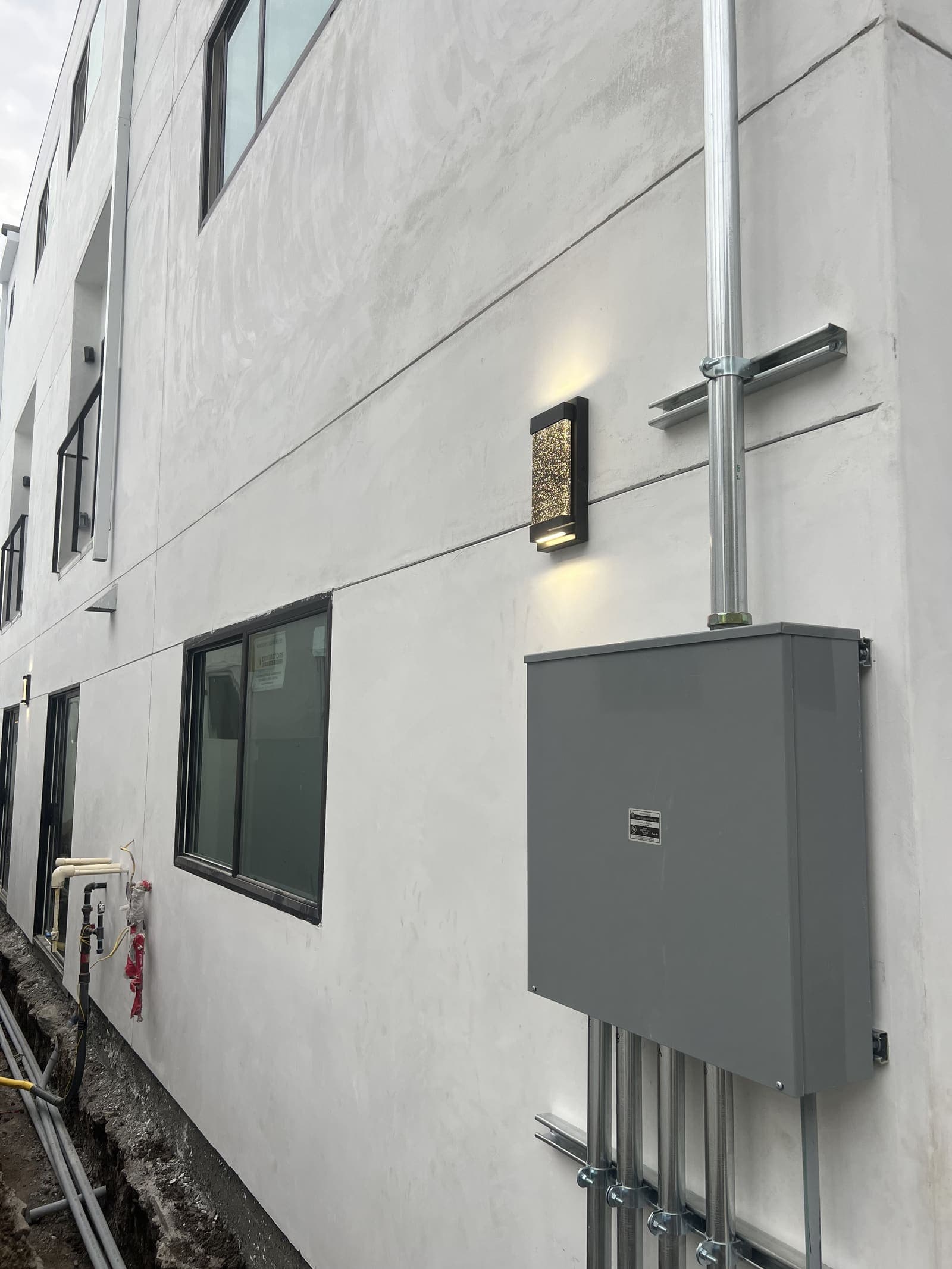 Finished commercial exterior wall with sconce lighting and gray service meter cabinet