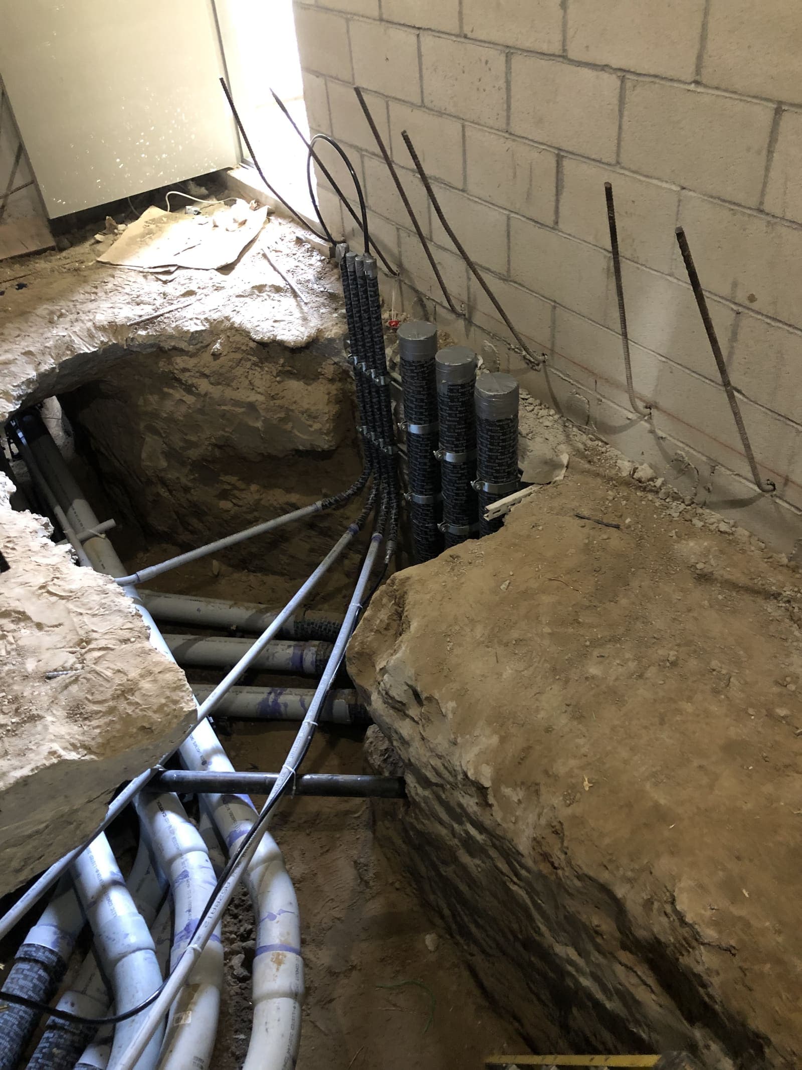 Conduit penetrations through a foundation wall with concrete cuts and rebar exposed