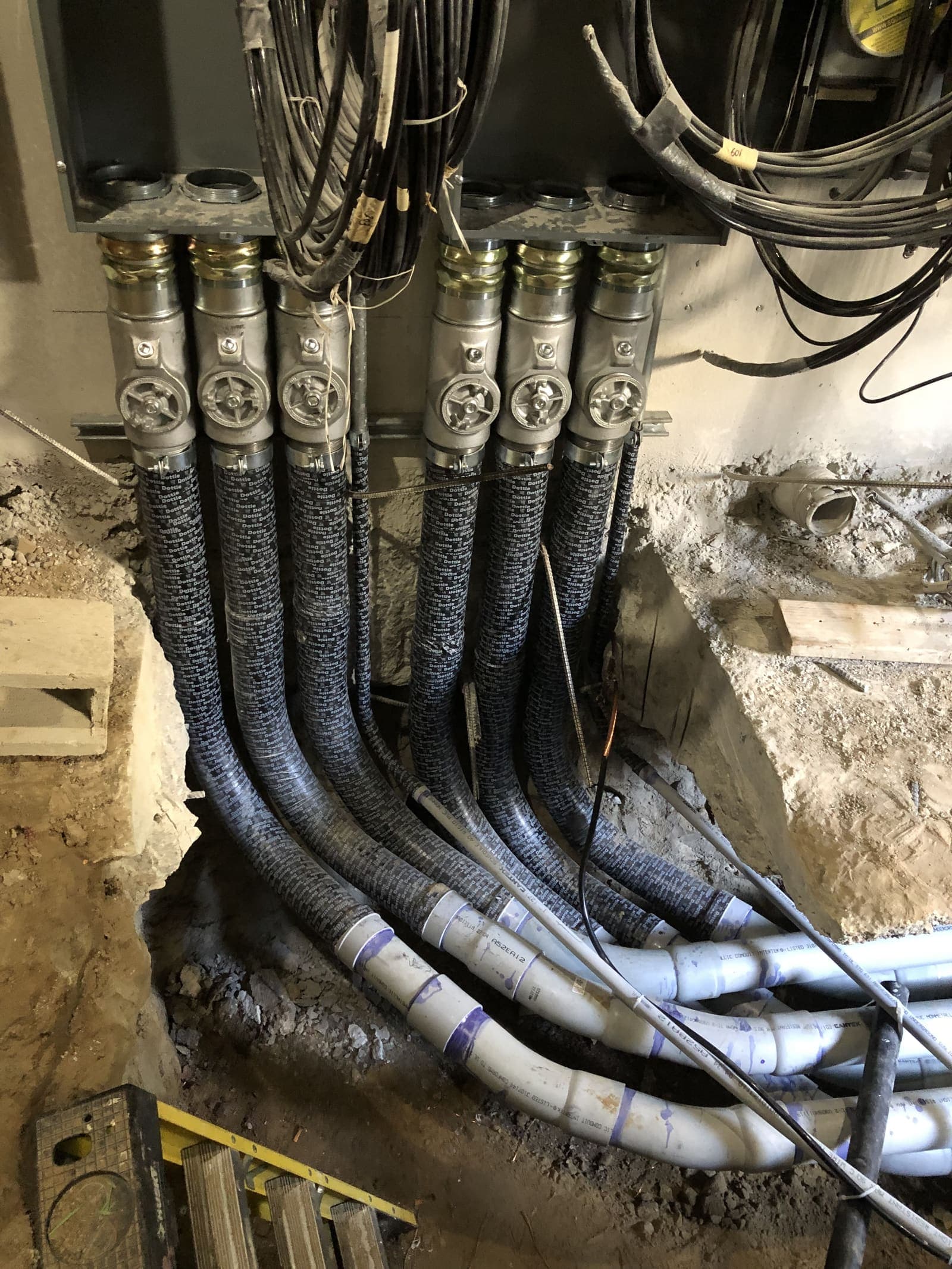 Large feeder conduits with metallic flex transitioning to PVC underground beneath switchgear