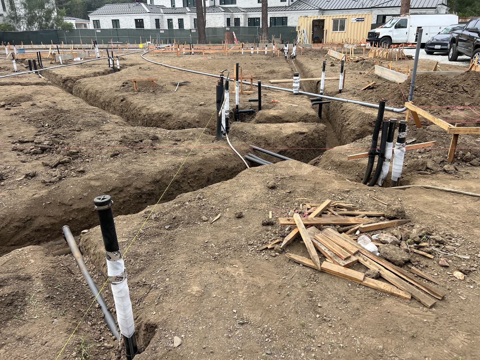 Excavated trenches at a residential slab with stub-up conduits ready for the pour